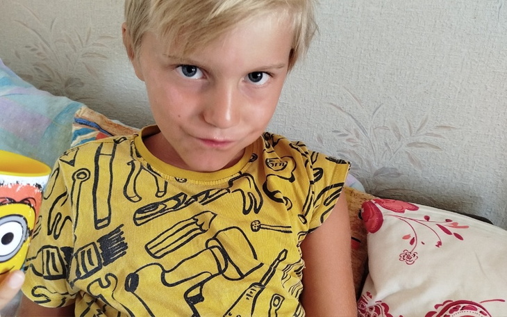 Chłopiec z uśmiechem, ubrany w żółtą koszulkę z narzędziami.