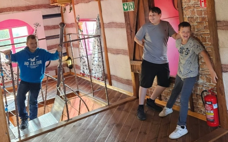 Trzech chłopców bawiących się w drewnianym domku.