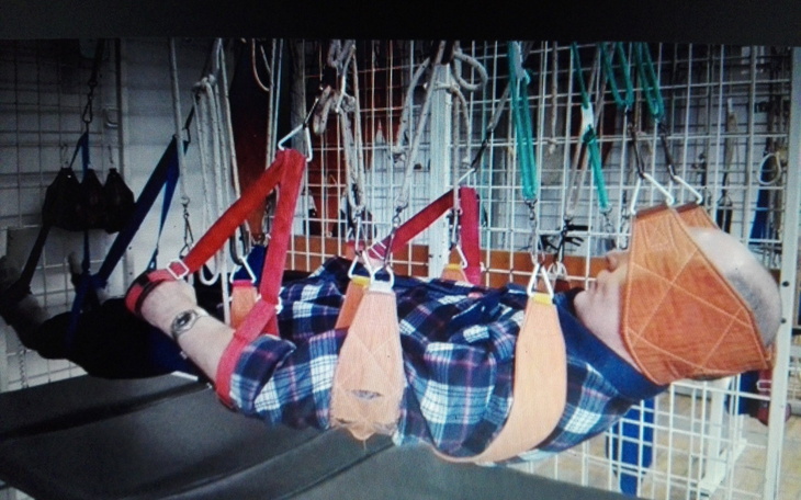 Osoba w uprzęży, zawieszona w powietrzu podczas terapii.