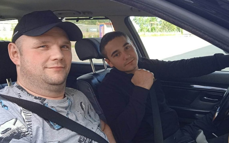 Dwóch mężczyzn w samochodzie, uśmiechnięci i zrelaksowani.