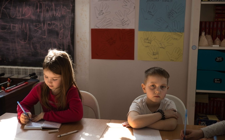 Dzieci w klasie, skupione na rysowaniu i pisaniu.