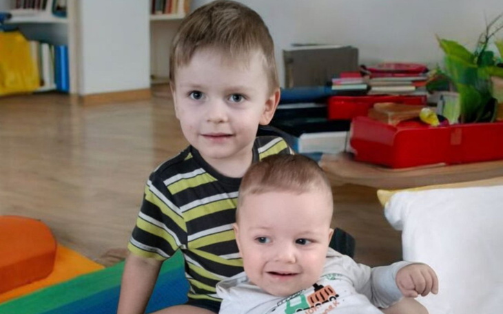 Dwoje małych dzieci siedzących na podłodze w kolorowym otoczeniu.