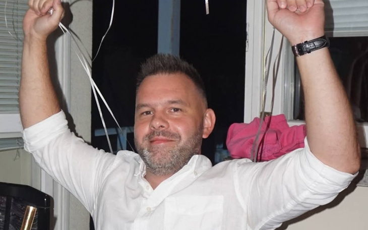 Mężczyzna świętujący z balonami w rękach.