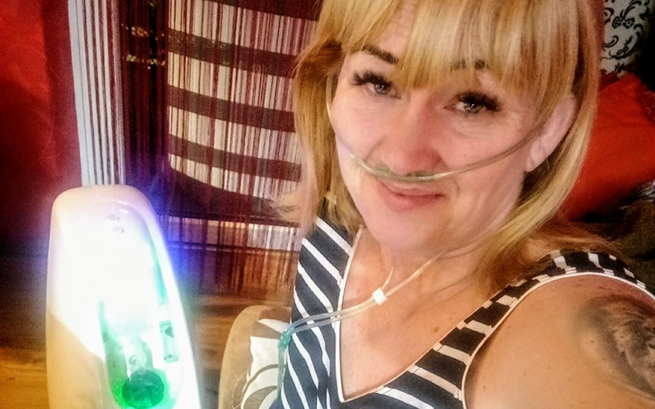 Kobieta z tlenem, uśmiechająca się do kamery.