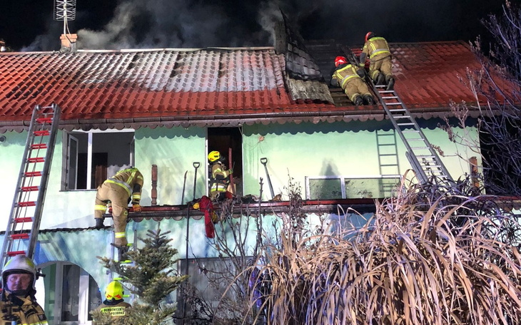 Strażacy gaszący pożar na dachu budynku.