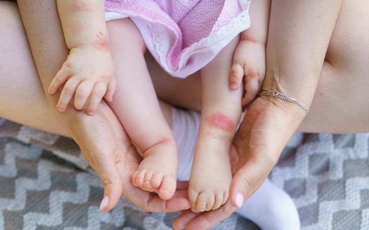Dziecięce stópki trzymane przez dorosłe ręce.