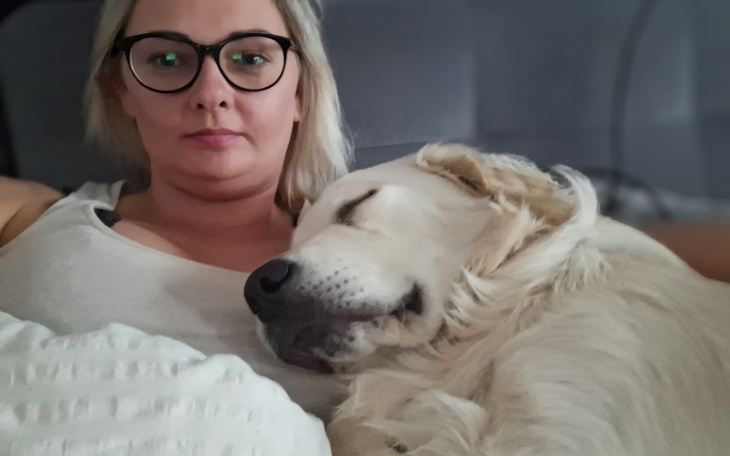 Kobieta leżąca z psem na kanapie.