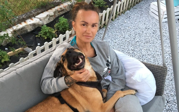 Kobieta siedząca z psem na kanapie w ogrodzie.