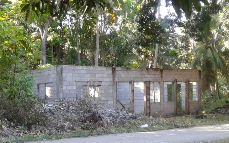 Niedokończony budynek otoczony zielenią w tropikalnym otoczeniu.