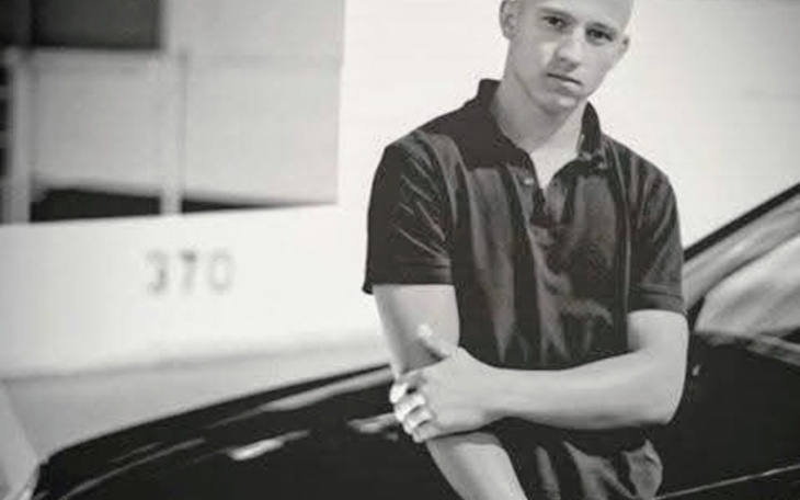 Młody mężczyzna pozujący przy samochodzie.