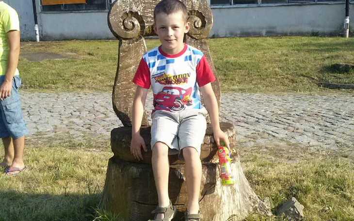 Chłopiec siedzący na dużym drewnianym krześle.