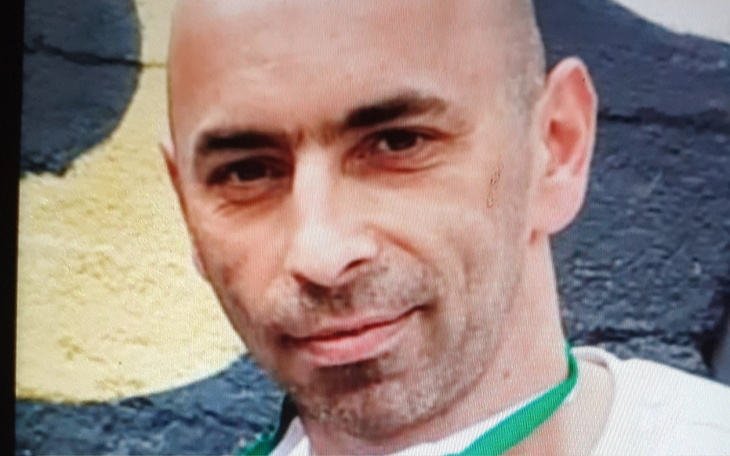 Mężczyzna z krótkimi włosami na tle graffiti.