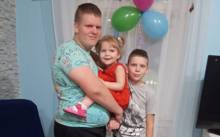 Rodzina z dziećmi w kolorowych balonach na przyjęciu urodzinowym.