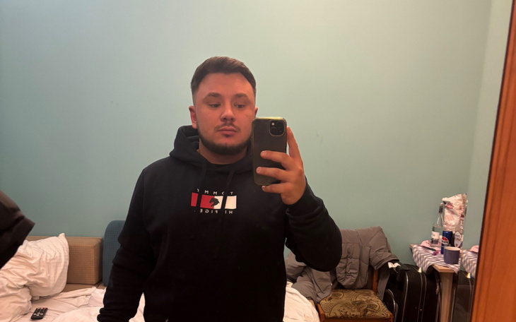 Mężczyzna robiący selfie w lustrze, w czarnej bluzie.