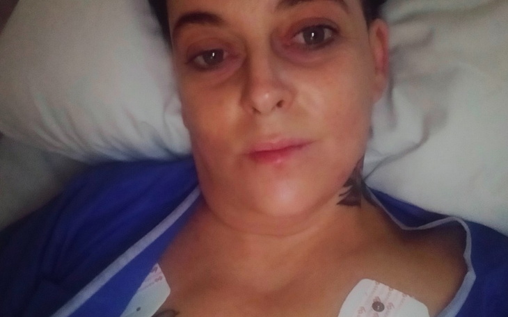 Kobieta leży na łóżku, wygląda na zmęczoną.