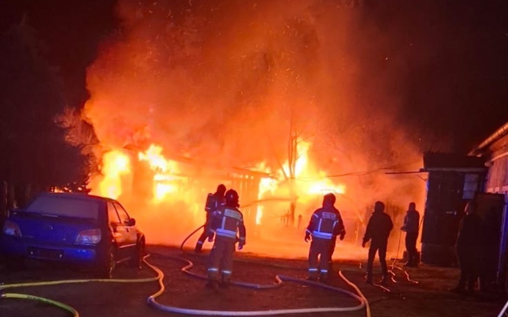 Pożar w nocy, strażacy gaszą płomienie.