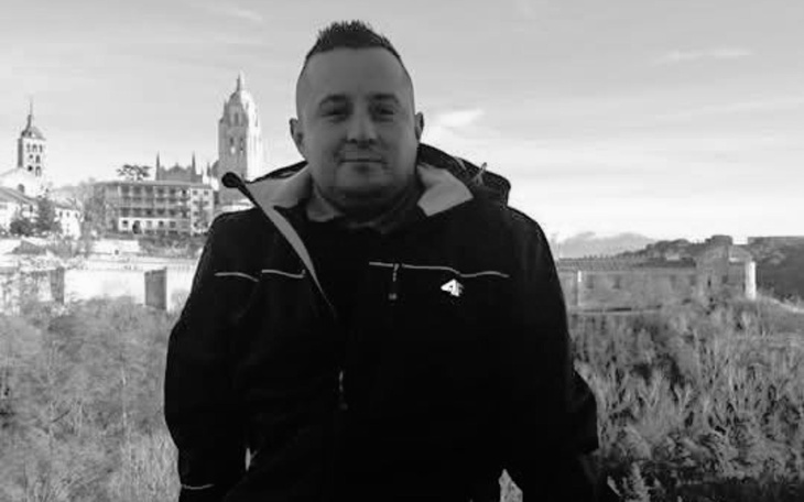 Mężczyzna w kurtce na tle krajobrazu z zabytkami.