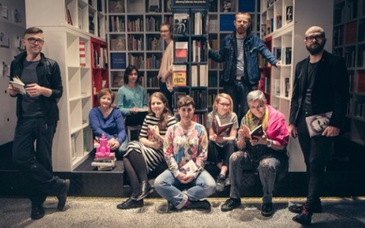 Grupa ludzi w bibliotece, czytających książki w przytulnej atmosferze.