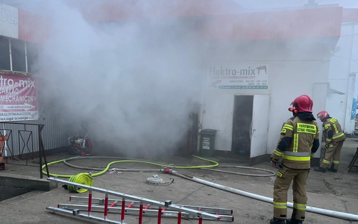 Strażacy walczą z pożarem w zadymionym budynku.