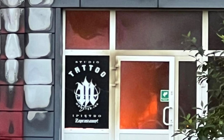 Wejście do studia tatuażu z logo na drzwiach.