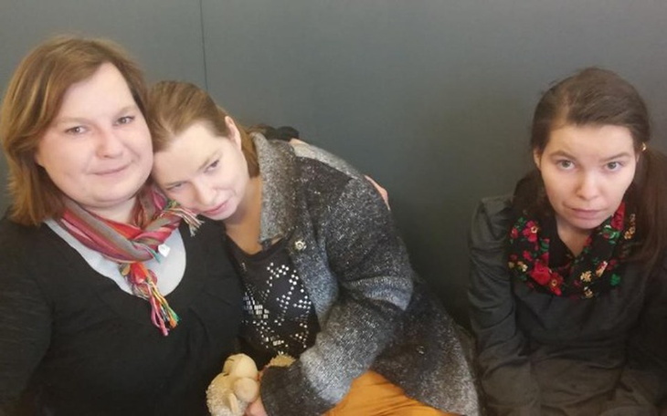 Trzy kobiety siedzące razem, jedna z nich trzyma maskotkę.