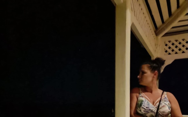 Kobieta stojąca w cieniu na tarasie w nocy.