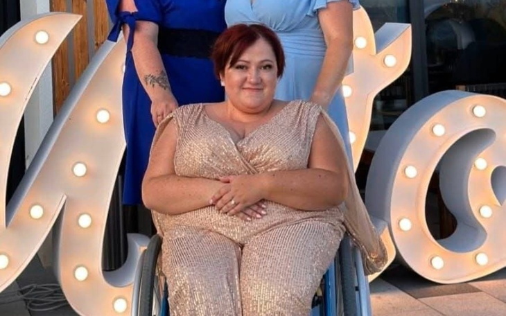 Kobieta w eleganckiej sukni, siedząca na wózku inwalidzkim.