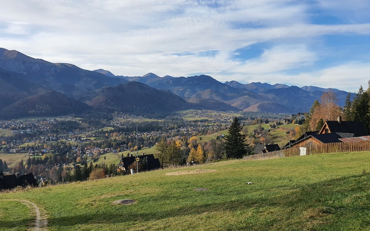 Widok na góry i dolinę, z domami w tle, w słoneczny dzień.