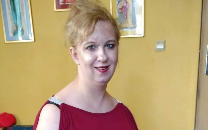 Kobieta w czerwonej sukience, uśmiechająca się do kamery.