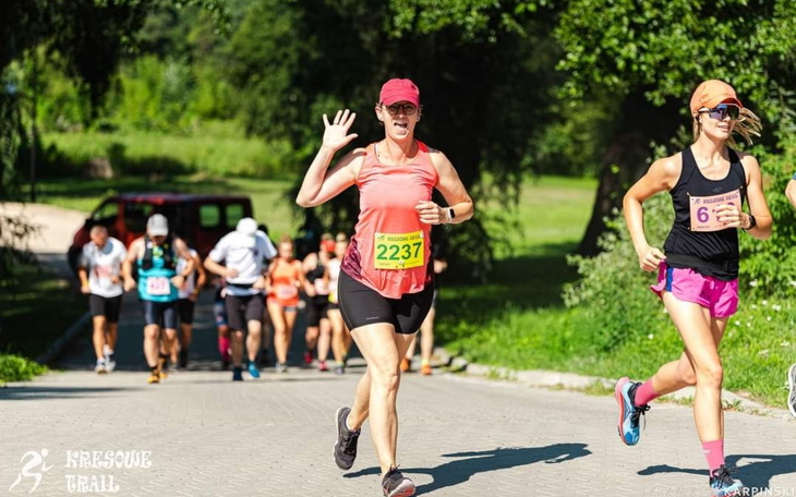 Biegacze na trasie, jeden z uczestników macha ręką.