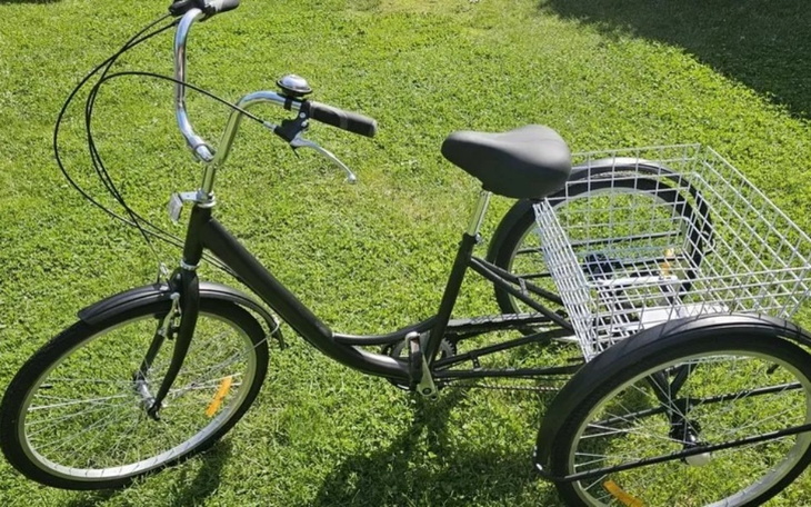 Rower z koszykiem na trawie, gotowy do jazdy.