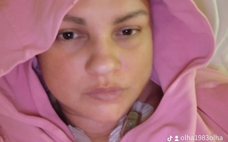 Kobieta w różowej bluzie, z zamyśloną miną.