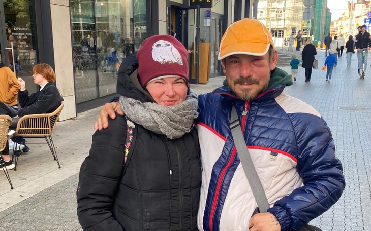 Para uśmiechniętych ludzi na ulicy, w ciepłych ubraniach.
