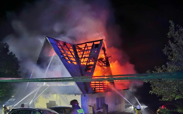 Pożar budynku, strażacy gaszą płomienie w nocy.