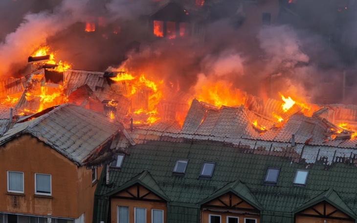 Pożar budynku, ogień trawi dach i ściany.