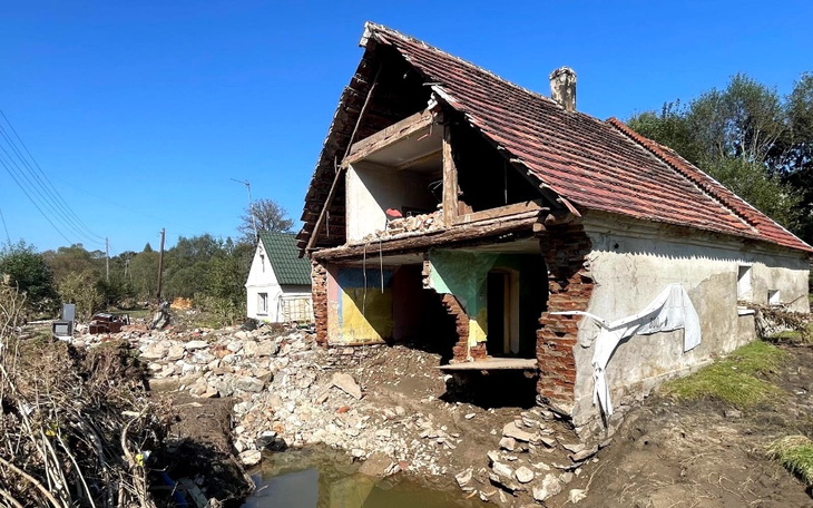 Zniszczony dom po powodzi, z odsłoniętymi ścianami i gruzem wokół.