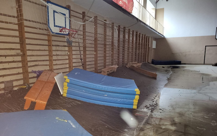 Zniszczona sala gimnastyczna z przewróconymi sprzętami.