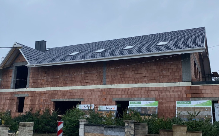 Budowa domu z drewnianą elewacją, z oknami na poddaszu.