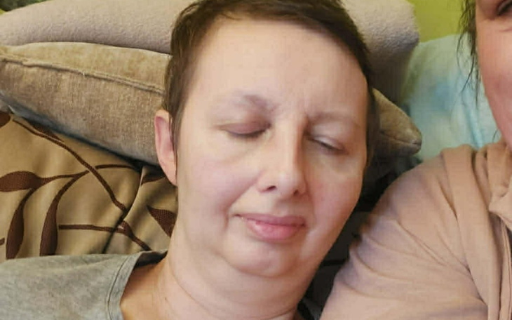 Kobieta z zamkniętymi oczami odpoczywa na kanapie.