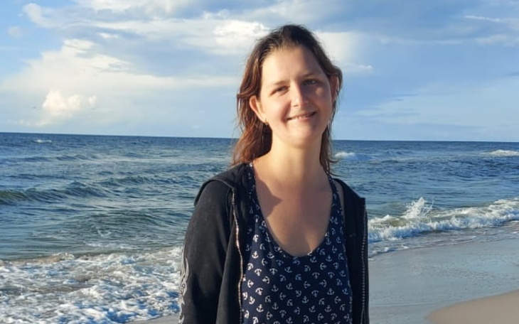 Młoda kobieta na plaży z falami w tle.