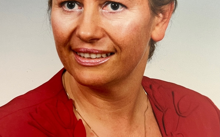 Portret kobiety w czerwonej bluzce, uśmiechnięta.