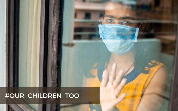 Młoda osoba w maseczce, patrzy przez okno.