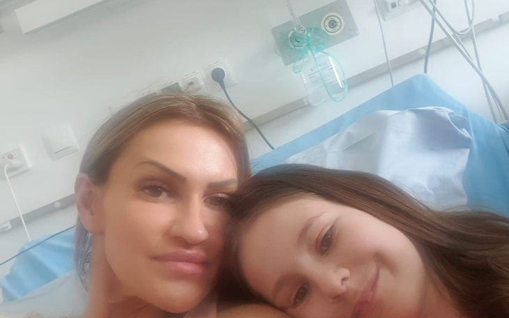 Dwie kobiety na oddziale szpitalnym, uśmiechnięte, na łóżku.