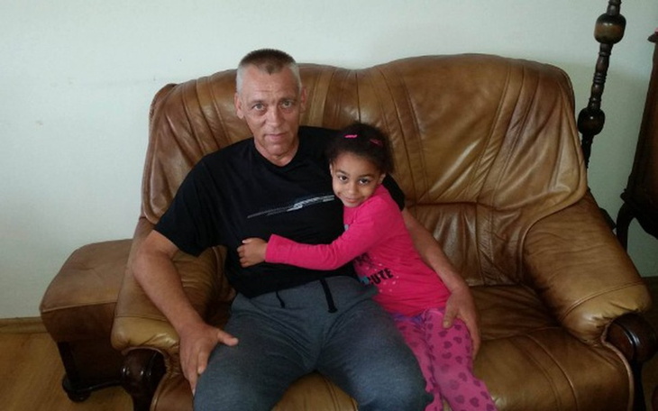 Starszy mężczyzna z uśmiechniętą dziewczynką na kanapie.