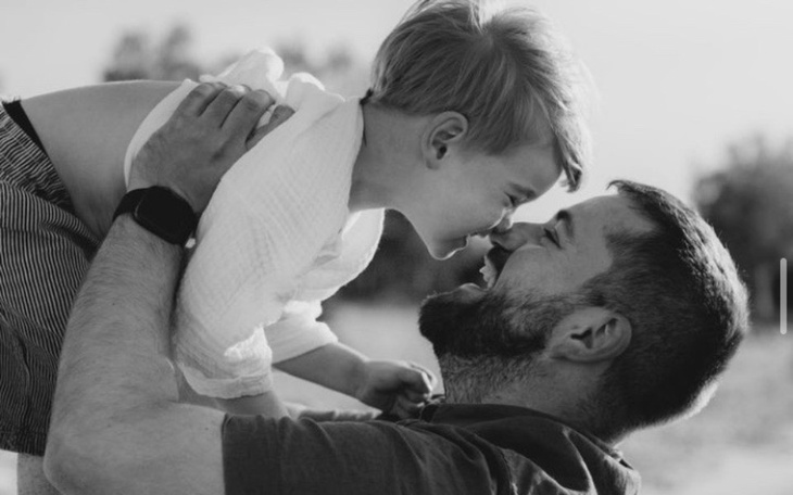Czarnobiałe zdjęcie ojca bawiącego się z dzieckiem.