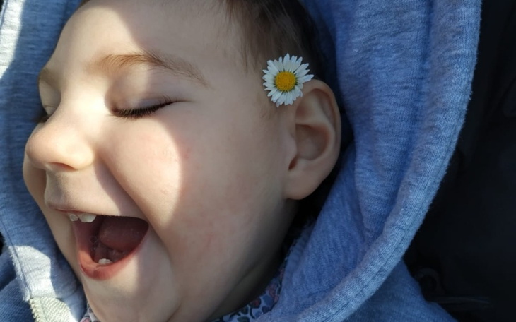 Uśmiechnięta dziewczynka z kwiatkiem w uchu.