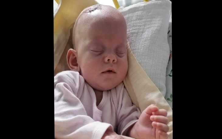 Noworodek śpiący w foteliku, spokojny wyraz twarzy.