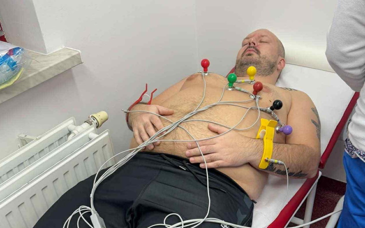 Mężczyzna leżący na łóżku z elektrodami na klatce piersiowej.