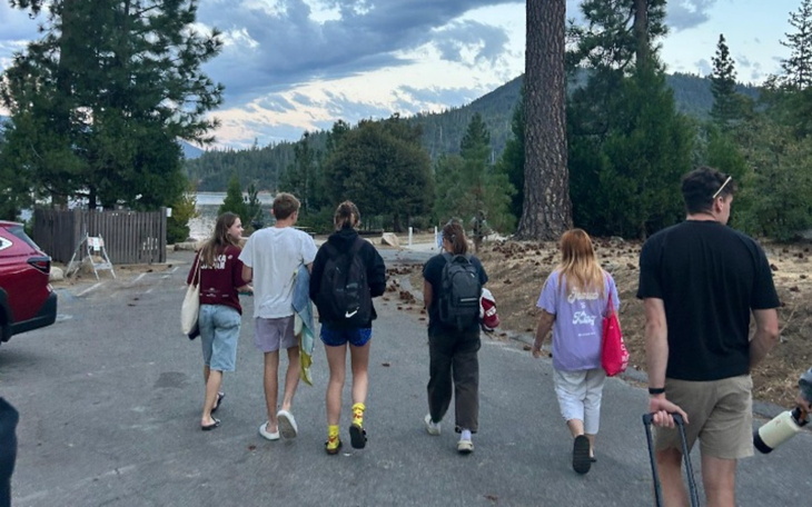 Grupa ludzi spacerujących wzdłuż drogi w lesie.