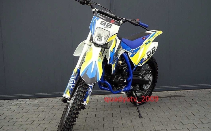 Motocykl wyścigowy w kolorze niebieskim i żółtym, na tle ciemnej ściany.